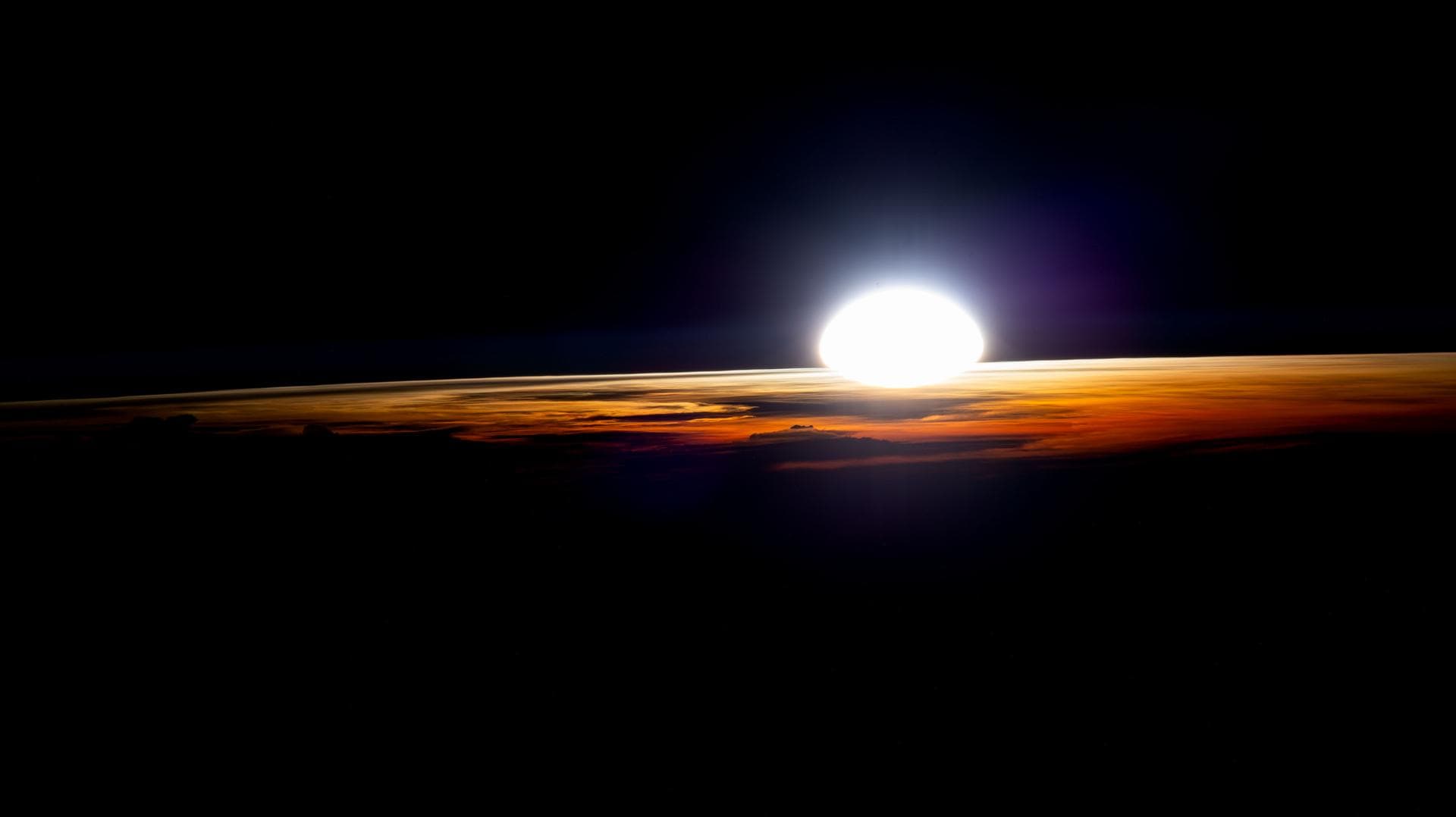 The Sun rising over Earth's curved horizon, seen from the International Space Station.