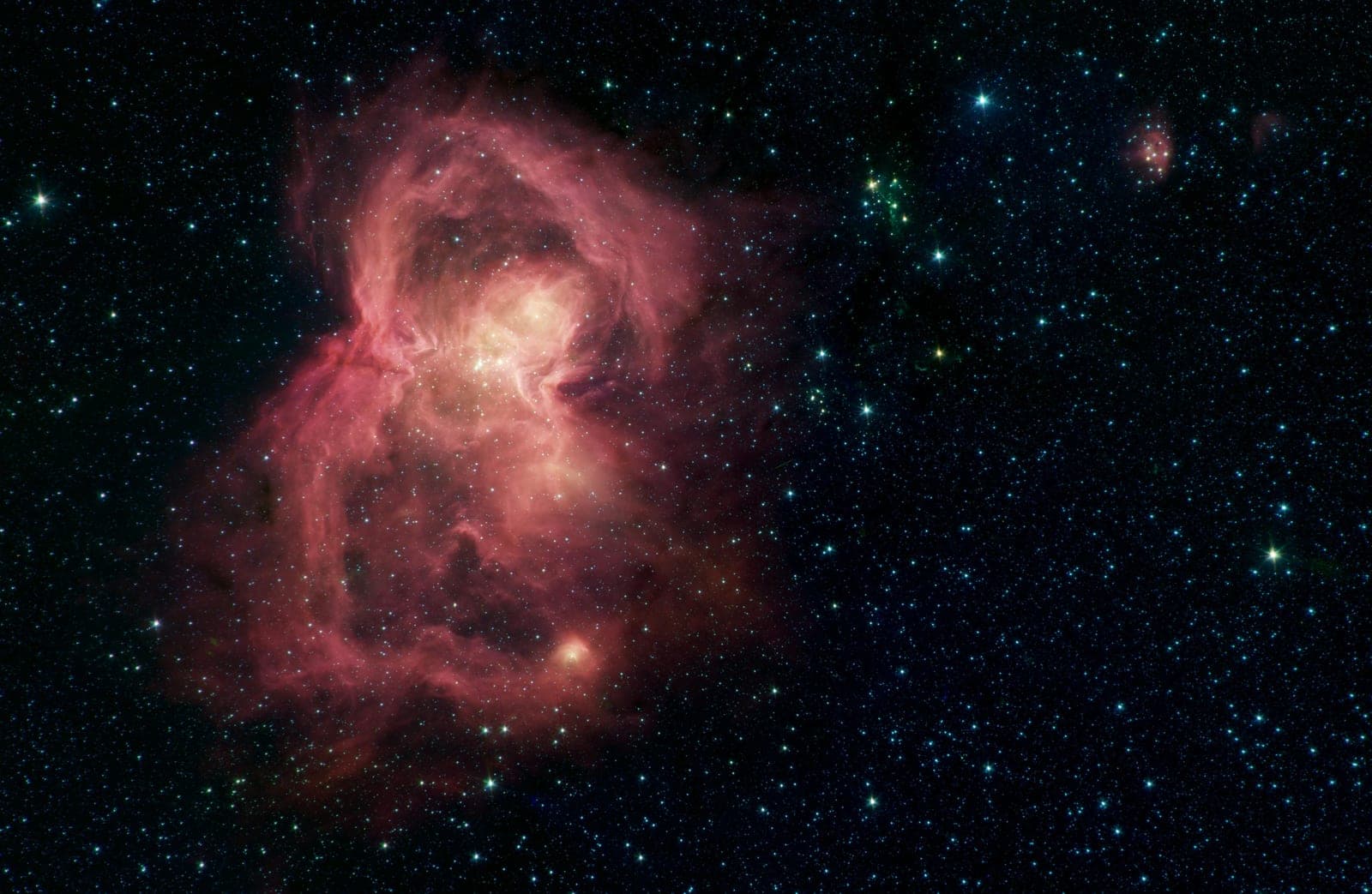 The nebula W40 in infrared: a pink cloud of gas and dust shaped like a butterfly among stars.